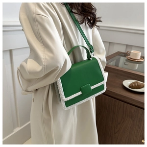 Green leather crossbody bag with white faux fur trim shown on a model in a cafe setting