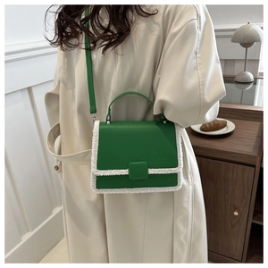 Detail of green square bag with white faux fur trim and adjustable shoulder strap