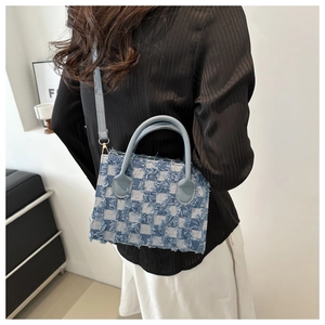 Detail view of denim checkerboard tote bag with fringe trim and shoulder strap