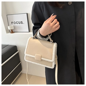 Detail of cream crossbody bag featuring faux fur trim and elegant square magnetic clasp