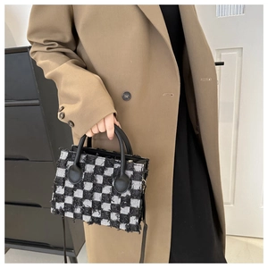 Detail of the black and white checkered tweed texture and round leather handle on the bag