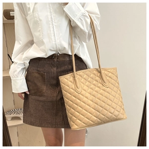 Close-up of beige quilted tote bag showing large diamond stitching and leather texture