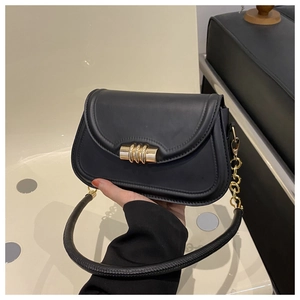 Detail view of the black leather saddle bag featuring a unique gold cylindrical lock and chain