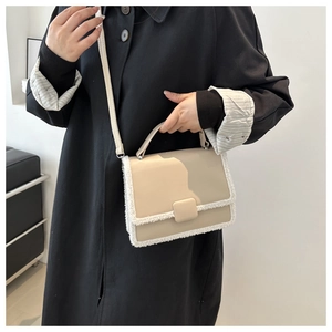 Detail view of cream leather crossbody bag with faux fur trim on model in black coat