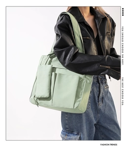 Close-up of mint green large capacity tote bag with matching pouch on black leather jacket
