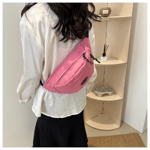 Close-up of pink canvas chest bag with adjustable black strap and brand logo detail