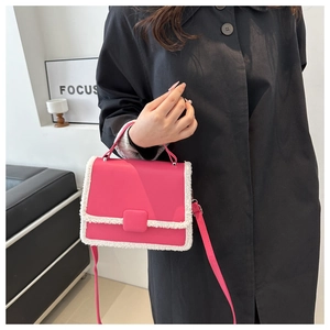 Detail of fuchsia crossbody bag with white faux fur trim styled on a black coat