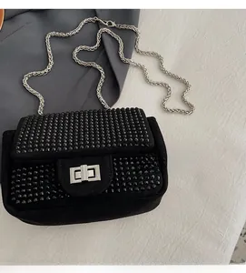 Detail of black crossbody bag with shimmering rhinestones and silver chain strap
