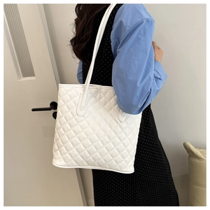 Close-up of white quilted tote bag featuring detailed diamond stitching and twin straps