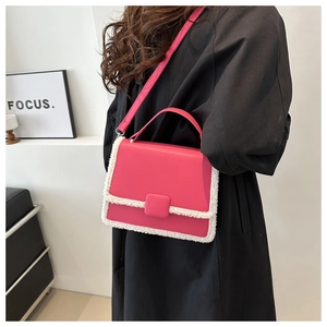Bright pink crossbody bag with white faux fur trim shown on a model in a modern interior