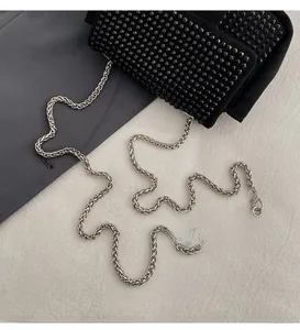 Detailed view of glossy black beads on a suede bag with a silver chain strap