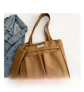 Detailed macro view of brown nylon tote bag with front pockets and matching coin pouch