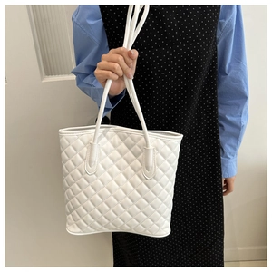 Detailed view of white quilted tote bag with classic stitching and sleek handle straps