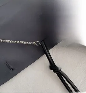 Détail du crochet métallique amovible et des strass brillants sur le sac de soirée noir