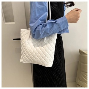 Detailed view of the white quilted diamond stitching and textured surface of the bucket bag