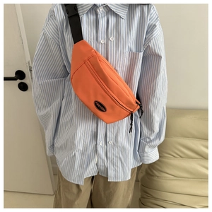 Detail of a bright orange canvas fanny pack with black FANYISSA logo and adjustable strap