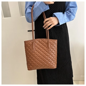Close-up of brown quilted faux leather bucket bag with diamond stitching and slim straps