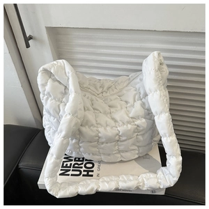 Detailed view of white quilted puffer shoulder bag with soft textured square pattern