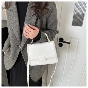 Detail view of white crossbody bag with plush faux fur trim and sleek square flap design