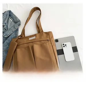 Brown nylon tote bag with dual front pockets and storage pouch shown with tablet