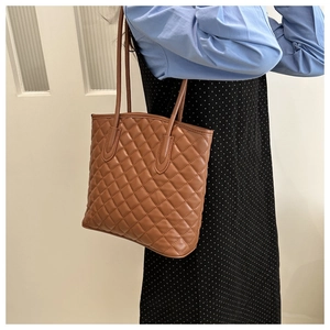 Close-up of brown quilted diamond pattern faux leather shoulder bag on a model