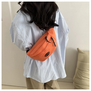 Rear view of model wearing an orange canvas waist bag with adjustable strap and logo