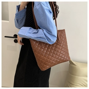 Detailed side view of a brown quilted tote bag with elegant rhombus stitching and straps