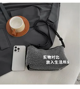 Détail du sac hobo noir en strass avec bandoulière nouée près d'un smartphone