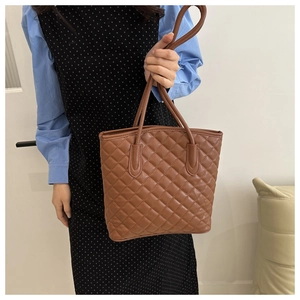 Close-up of brown quilted tote bag showing diamond stitch texture and slim shoulder straps