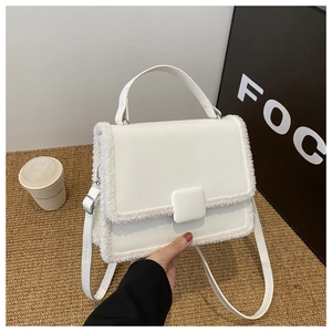 Detailed close-up of white crossbody bag featuring cozy faux shearling trim and metal clasp
