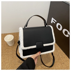 Detail shot of black leather handbag with white faux fur trim and square buckle accent