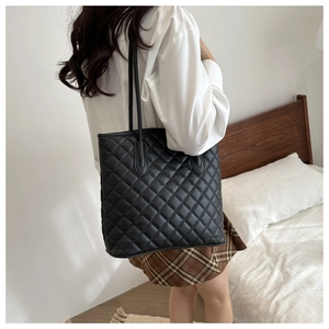 Close-up of black quilted tote bag with diamond stitching and slim leather shoulder straps