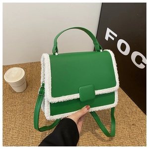 Detail of green crossbody bag featuring white faux fur trim and rectangular flap closure