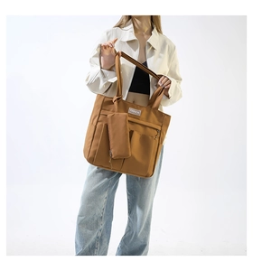 Brown nylon tote bag with hanging pouch shown on model in a studio setting