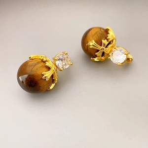 Vintage gold earrings featuring round tiger eye stones and cross floral carvings