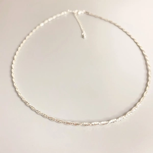 Minimalist silver twist rope necklace with adjustable lobster clasp on grey background