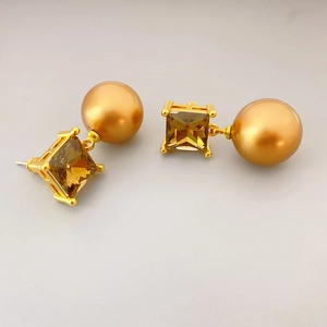 Detailed macro view of square amber crystal stud and lustrous golden pearl drop earring