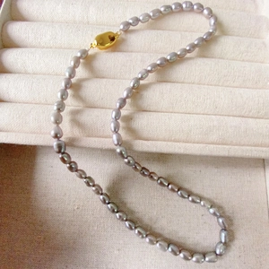 Collier élégant en perles d'eau douce irisées grises avec fermoir doré sur velours beige