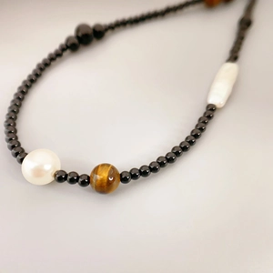Collier en perles baroques et agate noire avec pierre oeil de tigre sur fond gris