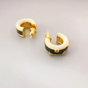 Minimalist C-shaped hoop earrings with cream and black enamel and gold metal studs