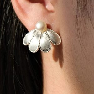 Macro side view of silver brushed flower petal earring with freshwater pearl