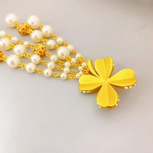 Collier de perles à quatre rangs avec pendentif trèfle doré mat et détails en strass
