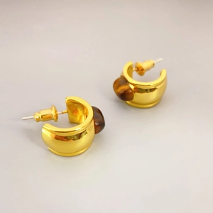 Golden C-shaped stud earrings with tiger eye stone inlays on a light grey background
