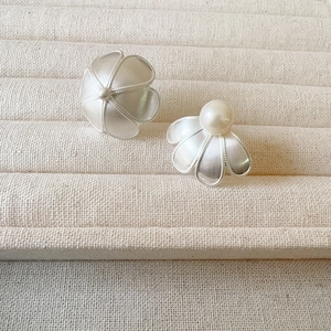 Elegant silver-tone flower earrings with freshwater pearl on a textured jewelry tray
