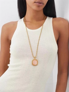 Detail of square pink crystal pendant on a gold twisted rope chain worn by a model
