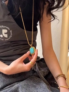 Detail view of gold square pendant necklace with blue turquoise and matching ring