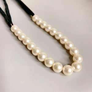 Close-up of elegant pearl necklace with black velvet cord and gold metal fasteners