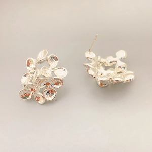 Macro shot of silver floral cluster stud earrings with layered metallic petals detail