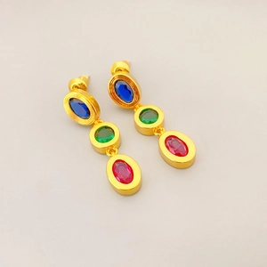 Close-up of gold-plated earrings featuring three-tier blue, green, and pink gemstones