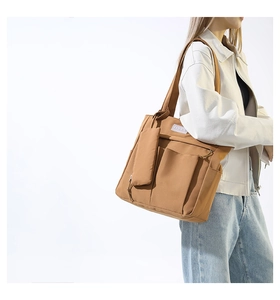 Detail view of brown canvas tote bag with functional pockets and a matching small pouch